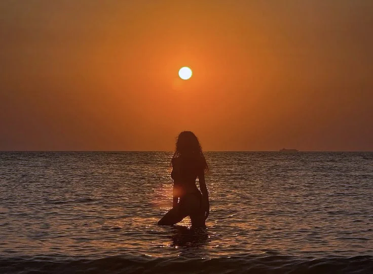Silueta de una mujer entrando en el mar al atardecer