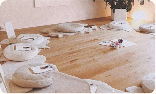 Sala preparada para un encuentro, con cojines y cuadernos en el suelo